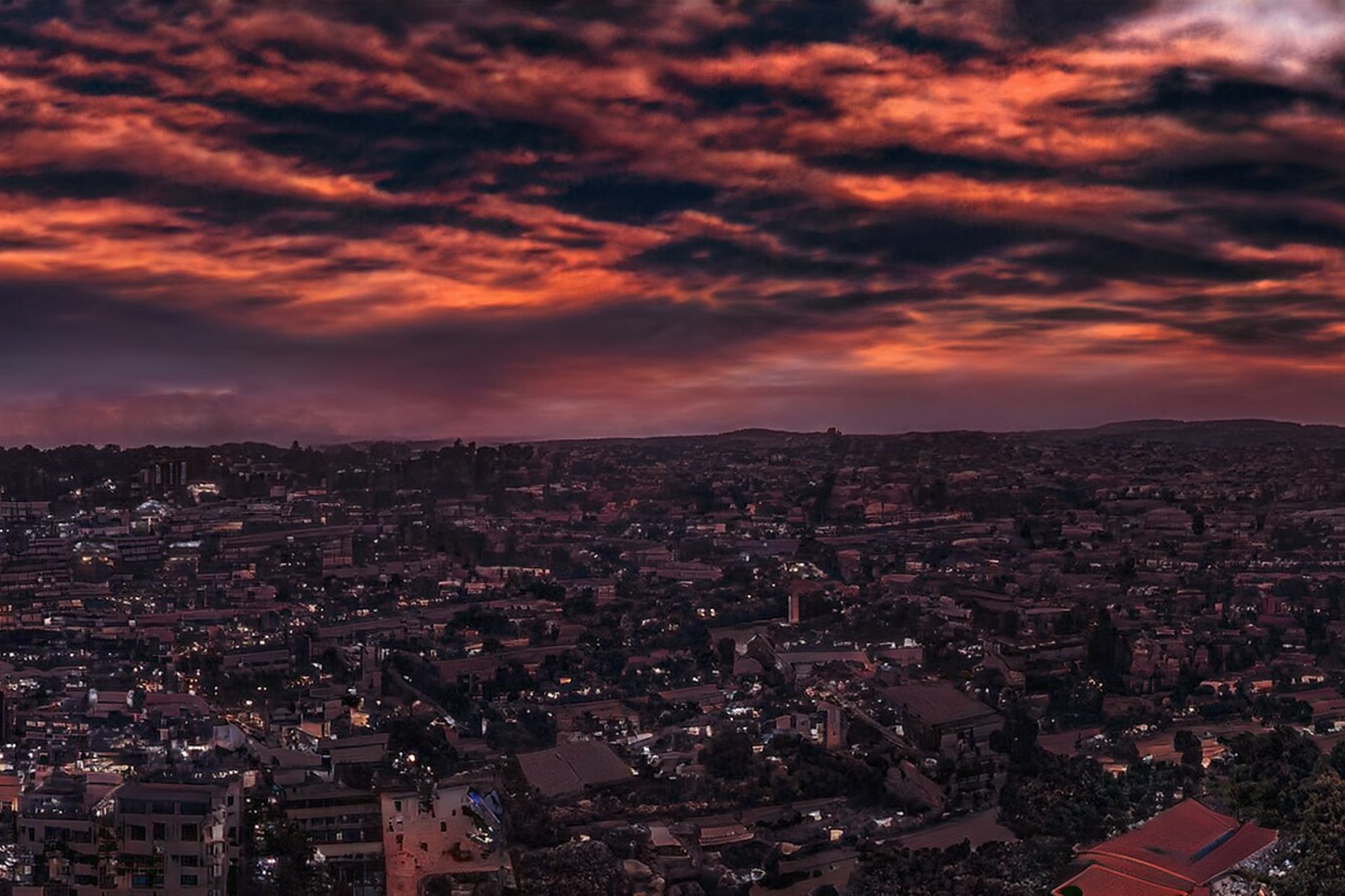 Rooftops of Kampala under a red sky at sunset