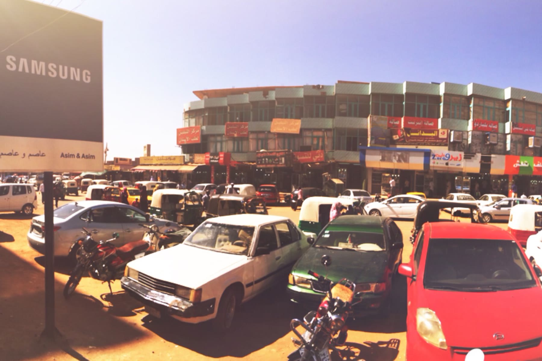 Shops and parked cars on a commercial street in Omdurman, Sudan