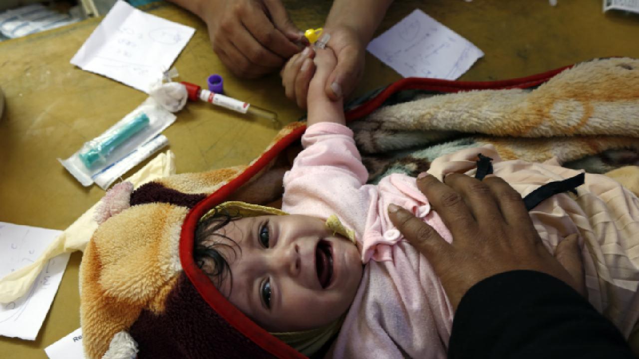 A health worker administers an oral cholera vaccine to an infant